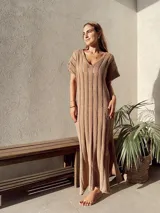 Vestido largo color beige, de tejido calado, escote en V, manga corta y corte holgado.