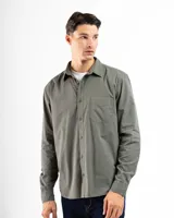 Camisa de manga larga color verde oliva, confeccionada en algodón. Tiene corte clásico, bolsillo en el lado izquierdo del pecho y cierre con botones.