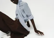 Blusa de manga larga color celeste claro con textura sutil, cuello alto con lazo largo incorporado que cae al frente.