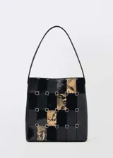 Bolso tipo tote de cuero negro con diseño patchwork que combina cuero liso, charol y estampado animal print. Tiene asa de hombro y cierre con mosquetón.