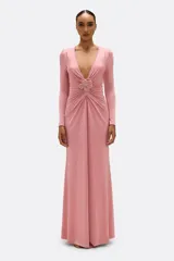 Vestido largo de jersey color rosa, con escote en V profundo y mangas largas. Presenta un drapeado en la parte delantera que se une a una flor bordada a mano.