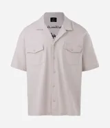 Camisa boxy color crema de algodón texturizado, con cuello inglés, mangas cortas, bolsillos delanteros y lettering bordado.