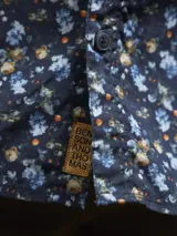 Camisa de hombre con estampado de flores en tonos azules y negros, de manga larga y corte regular.