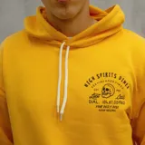 Canguro amarillo con capucha y cordones blancos, bolsillo tipo canguro y estampado frontal con texto y calavera.