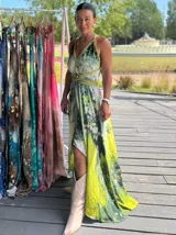 Vestido largo de tela fluida, color verde esmeralda con estampado abstracto en tonos turquesa y detalles dorados. Diseño asimétrico con un solo tirante tejido en el hombro.