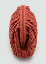 Bolso de mano tipo clutch color beige, tejido en fibra natural. Tiene asa larga desmontable para usar como bandolera, cierre a presión y forro interior.