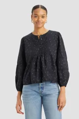 Blusa negra de algodón con estampado floral, cuello redondo con abertura y botones, mangas largas abullonadas con detalles de encaje y corte holgado.