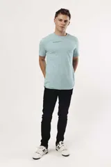 Remera de algodón color naranja claro con cuello redondo y manga corta. Presenta un pequeño estampado gráfico de temática playera en el pecho izquierdo.