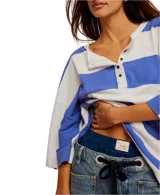 Remera de corte extragrande a rayas horizontales amarillas y blancas, confeccionada en jersey de peso medio, con textura suave y hombros caídos para un look relajado. Presenta un cierre frontal parcial con botón y terminaciones simples.