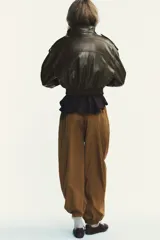 Pantalón de tiro medio color marrón claro, con cintura elástica, bolsillos laterales ocultos y puños elásticos.