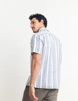 Camisa de manga corta a rayas verticales color natural y azul, con cuello clásico y cierre frontal con botones.