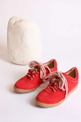 Zapatillas bajas marrones de gamuza con cordones y detalle de aplique de fresa en los cordones.