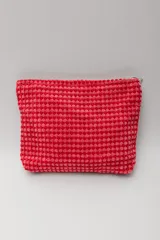 Neceser rectangular de tejido bouclé color coral, con cierre superior de cremallera plateada.