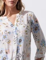 Blusa de gasa estampada con rayas verticales en tonos naranja, amarillo y blanco. Tiene cuello a la base, escote en V y botones. Delantera con bolsillo aplicado. Largo de manga regulable con presilla y botón. Terminación anudada opcional.