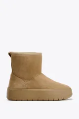 Botín color beige de caña baja, con interior de efecto pelo y suela tipo flatforma.