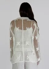 Camisa beige de crochet con cuello clásico, manga larga y cierre frontal con botones.