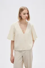 Blusa color crema de viscosa con escote en V y mangas cortas acampanadas.