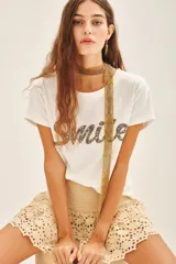 Remera blanca de algodón con bordado frontal de mostacillas metálicas formando la palabra "Smile".
