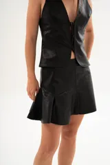 Minifalda negra de cuero vacuno italiano, con corte a la cintura y volados en el ruedo.
