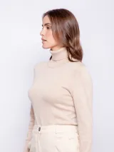 Polera de punto color beige con detalle de botones en las mangas y cuello alto.