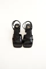 Sandalias plateadas de cuero, con tiras cruzadas sobre el empeine, pulsera al tobillo con hebilla y taco bajo cuadrado.
