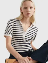 Chomba de corte amplio con diseño de rayas horizontales en blanco y azul marino. Tiene cuello en V y mangas cortas.
