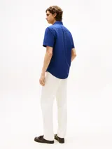 Camisa Oxford de manga corta color azul con cuello abotonado y logo de Tommy Hilfiger bordado en el pecho. Confeccionada en algodón Oxford con acabado teñido en prenda que le brinda un efecto lavado y un look veraniego.