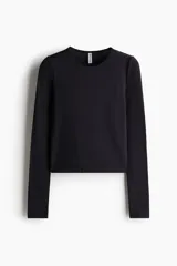 Remera corta negra de punto elástico, entallada, con cuello redondo y mangas largas.