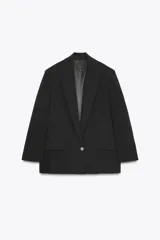 Blazer negro de corte oversize, con cuello solapa, escote pico, manga larga con hombreras y forro interior. Presenta bolsillos con solapa delanteros y bolsillo de vivo en el pecho.