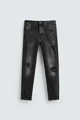 Pantalón de jean negro ajustado al cuerpo desde la cintura hasta el tobillo, de tiro medio y tejido elástico. Diseño de cinco bolsillos con lavado efecto roto y cierre frontal con cremallera y botón.