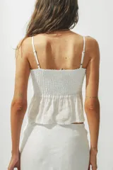 Top blanco con breteles finos y detalle de nudo en el centro del busto.