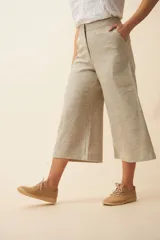 Pantalón palazzo color beige, de tiro alto, con bolsillos laterales y largo a la pantorrilla.