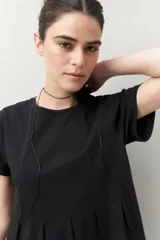 Remera blanca de manga corta con cuello redondo y costuras verticales en el frente.