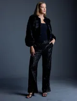 Chaqueta corta (crop) de piel sintética negra, con mangas largas abullonadas y abertura frontal.