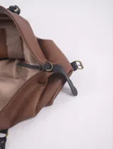 Bolso negro con detalles en cuero marrón, con doble asa de mano y cierre superior.