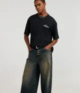 Pantalón mega baggy masculino confeccionado en jeans azul oscuro con efecto degradado. Presenta cintura con trabillas y detalles de argollas metálicas.