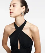 Vestido corto negro con cuello halter cruzado, lazo en el cuello y detalle cutout en el abdomen. Sin mangas y espalda descubierta. Ajustado al cuerpo.
