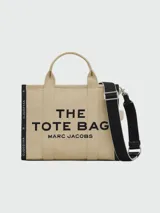 Bolso tote de tela color beige con estampado del logo de la marca en negro. Tiene doble asa de mano y correa de hombro extraíble y ajustable en color negro.