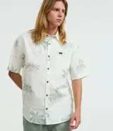 Camisa de hombre de corte relajado, color blanco con estampado de palmeras y paisajes playeros. Tiene cuello inglés, manga corta, abotonadura frontal y bolsillo en el pecho.