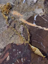 Collar dorado con cadena de eslabones alargados y dije de pez con escamas y cristales.
