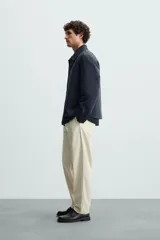 Pantalón chino color beige, corte recto, con bolsillos laterales y traseros. Cierre frontal con cremallera y botón.