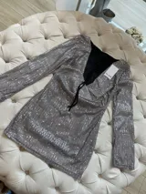 Vestido corto plateado de lentejuelas con mangas largas acampanadas y espalda descubierta que se ata con tiras.