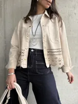 Sobrecamisa color beige de gamuza sintética con cuello camisero, cierre frontal con botones dorados, bolsillos de parche en el pecho y bajo con calados.