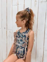 Traje de baño entero azul con estampado de leopardos y flores, con volados en los laterales. Incluye scrunchie para el pelo con el mismo estampado.