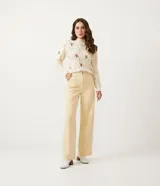 Suéter de punto color crema con cuello alto, textura de pompones y bordados florales.