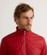 Chaqueta bomber roja de poliéster engomado, con cuello, puños y cintura acanalados a rayas blancas y azul marino. Tiene cierre frontal con cremallera y bolsillos laterales con cremallera.