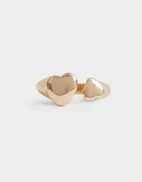 Anillo dorado con dos corazones grandes en los extremos.