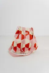 Bolso tipo bucket tejido con diseño geométrico en tonos lila, celeste y amarillo. Tiene cordón ajustable y correa ancha al tono para llevar al hombro o cruzado.