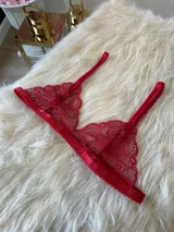 Conjunto de lencería rojo de encaje, compuesto por un bralette triangular con breteles regulables y una tanga regulable con corte media less y entrepierna de algodón.