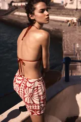 Short de tela color blanco con estampado de flores rojas, cintura elástica con cordón ajustable y bolsillos laterales.
